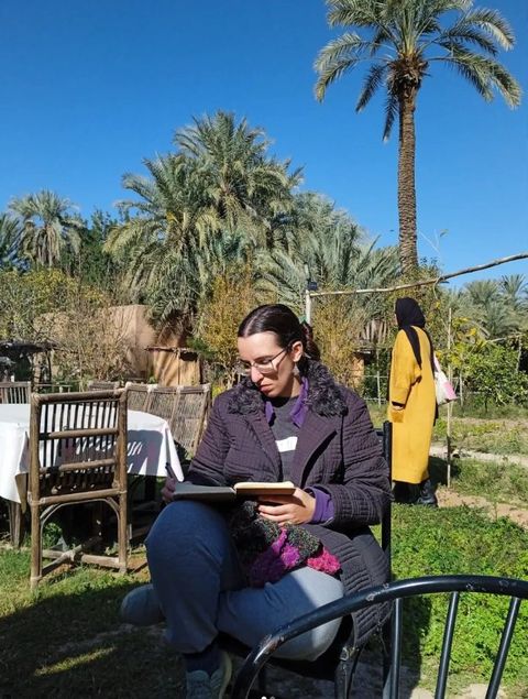Teresa Gubern leyendo al aire libre, sentada entre palmeras