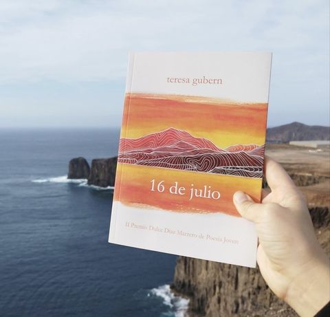 Ejemplar de 16 de julio sostenido en la mano frente al acantilado y el mar